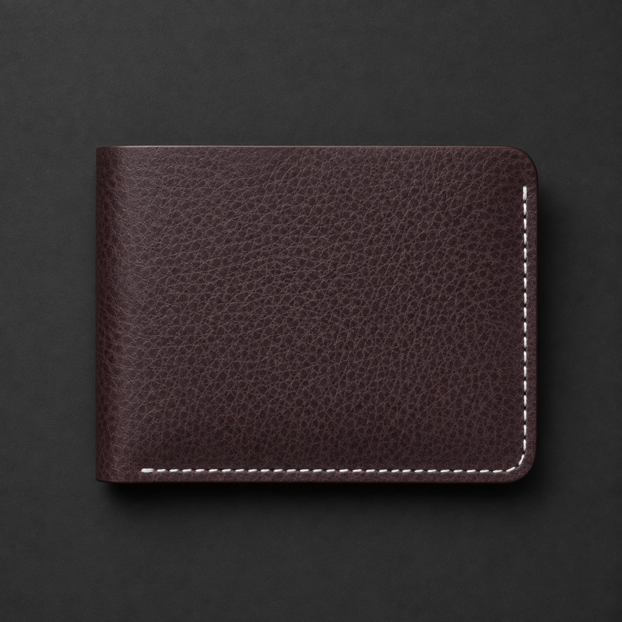 A dark brown textured leather bifold wallet with white contrast stitching, shown closed on a dark gray background.